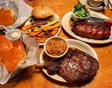 Texas Roadhouse meal spread featuring steaks, ribs, rolls with cinnamon butter, and sides, showcasing popular dishes available for delivery